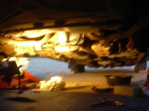 1996 Ford Crown Victoria - The underside of a vehicle is illuminated, showing various mechanical components and tools on the ground.