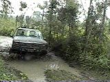 1980 Ford Bronco - 1980 Ford Bronco driving through a muddy off-road path.