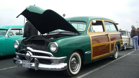 1990 Ford Probe - A classic green woody station wagon is displayed with its hood open, parked in a lot with other vehicles.