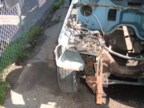 1990 Ford Ranger - The front section of a disassembled vehicle, revealing its internal structure and engine components, with a chain-link fence in the backgro…