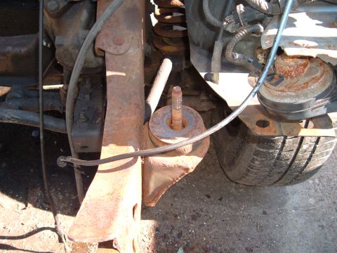 1990 Ford Ranger - Close-up view of heavily rusted suspension components and a tire, suggesting a vehicle in need of repair or restoration.