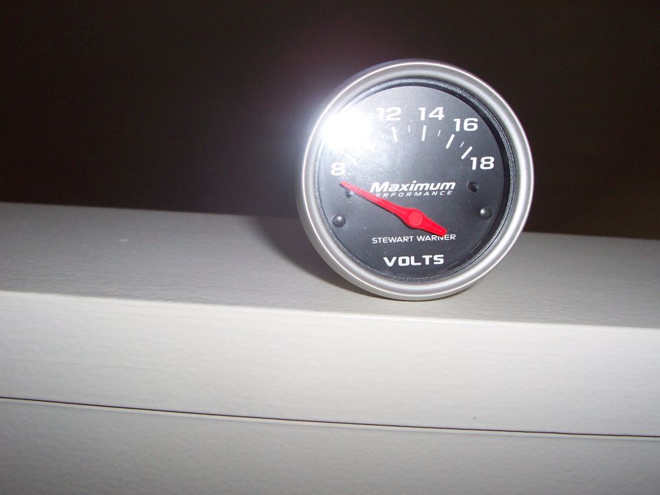 Stewart Warner volts gauge with red needle pointing to 8