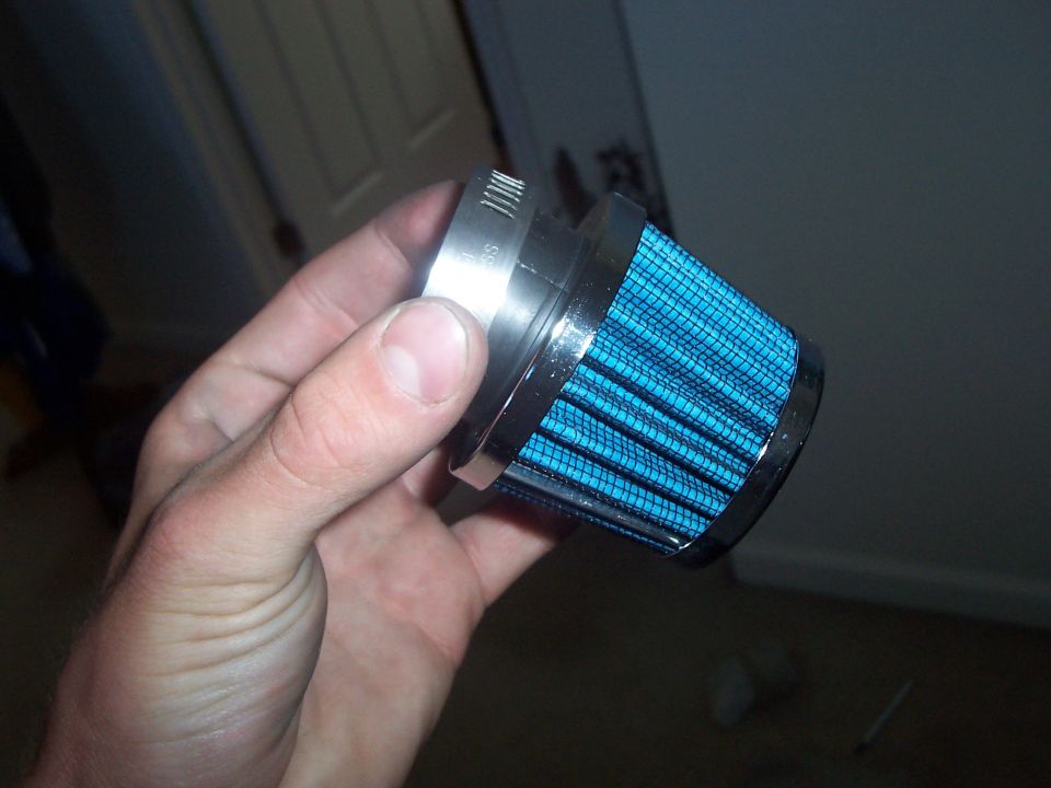 Hand holding a blue cone air filter with a metal clamp
