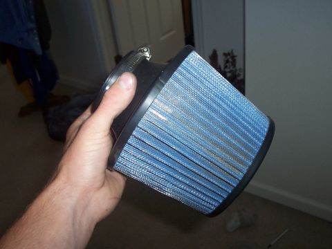 1993 Ford Probe - A hand holds a blue cone air filter with a metal clamp, indoors.