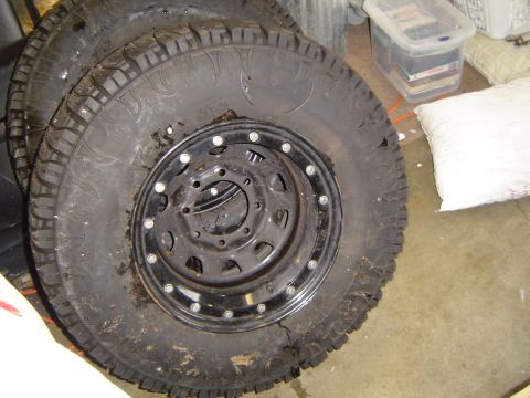 1978 Ford Bronco - Several off-road tires and rims are piled up indoors.