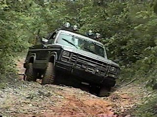 1980 Ford Bronco - 1980 Ford Bronco navigating a rough, wooded trail.