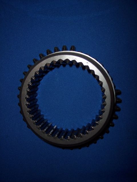 1972 Ford Ranchero - A close-up view of a metal gear synchronizer ring, likely a transmission component, against a solid blue backdrop.
