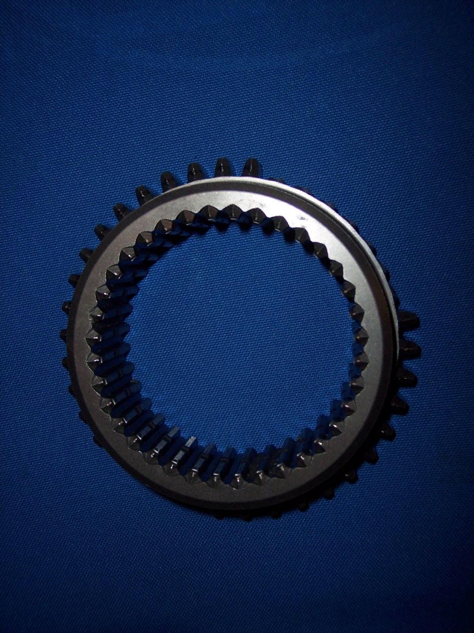 Gear synchronizer ring with internal teeth on a blue background