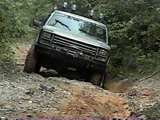 1980 Ford Bronco - This 1980 Ford Bronco navigates a challenging off-road trail with a prominent grille and roof-mounted lights.