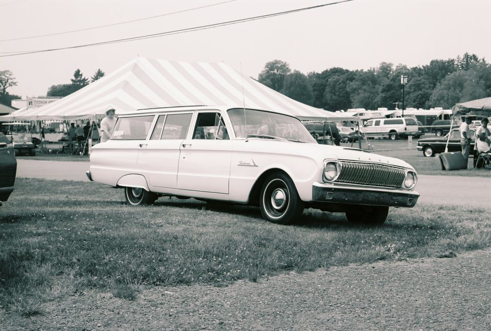 Black-and-white photo of a 1960s Ford Falcon station wagon at a car show