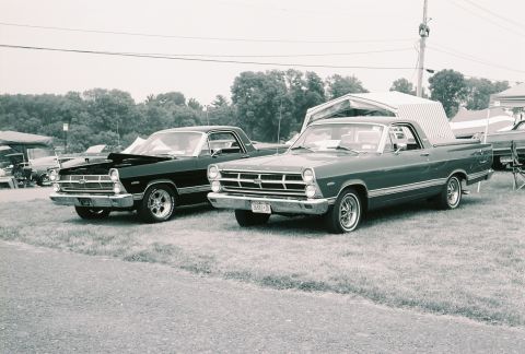 1973 Ford Ranchero - Two Ford Rancheros, a dark one and a green one, are displayed outdoors, possibly at a car show.