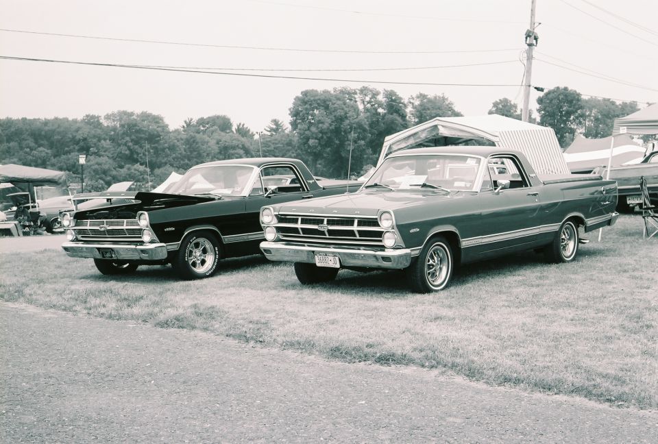 Two 1966 Ford Rancheros parked side-by-side, one dark, one green
