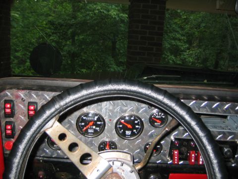 1979 Ford Bronco - The interior of a vehicle features a diamond plate dashboard with multiple gauges and red toggle switches.