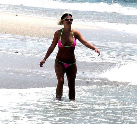 1991 Ford Bronco - A woman enjoys a day at the beach, wading in the shallow ocean water while wearing a pink bikini.
