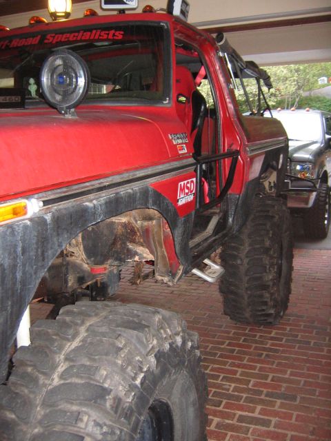 1979 Ford Bronco - Detail of a red lifted Ford truck showing Off-Road Specialists windshield banner, MSD decal and oversized tires.