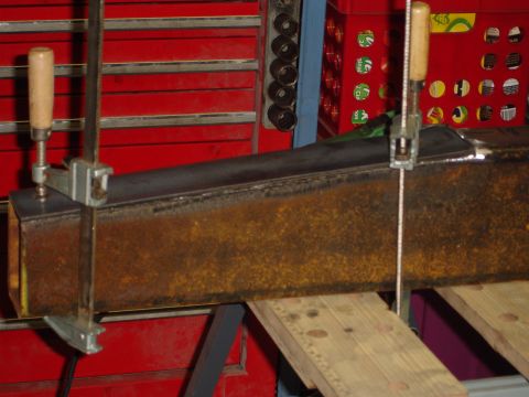 1989 Ford Bronco - Metal beam being worked on, clamped to a workbench with red tool chests visible.