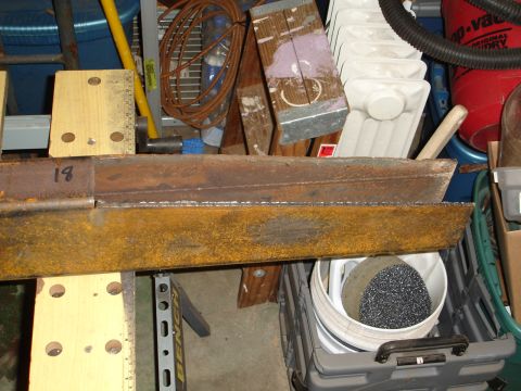 1989 Ford Bronco - A close-up view of metal fabrication parts and workshop clutter, with a white bucket containing dark material.