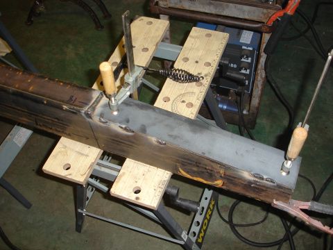 1989 Ford Bronco - Metal beam being welded on a workbench, with clamps and welding equipment visible.