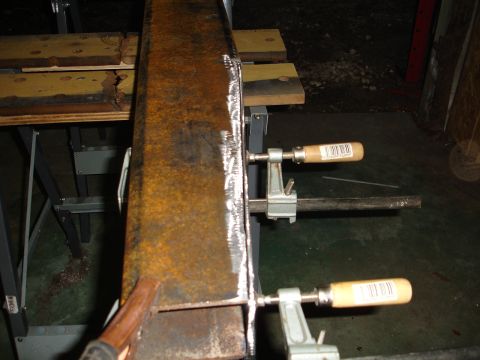 1989 Ford Bronco - A close-up view of a rusted metal beam being held by clamps, ready for fabrication or repair.