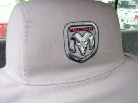 1996 Dodge 2500 - Close-up of a Dodge Ram logo on a vehicle headrest. Another truck is visible outside.