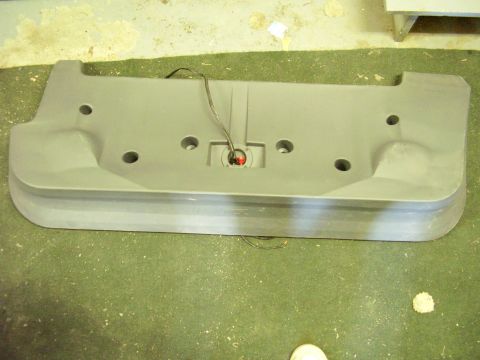 1996 Dodge 2500 - A gray plastic bumper part with wiring and a red light is shown on a green floor.
