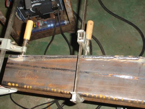 1989 Ford Bronco - Metal beams are clamped in place, prepared for welding with a welding machine nearby.