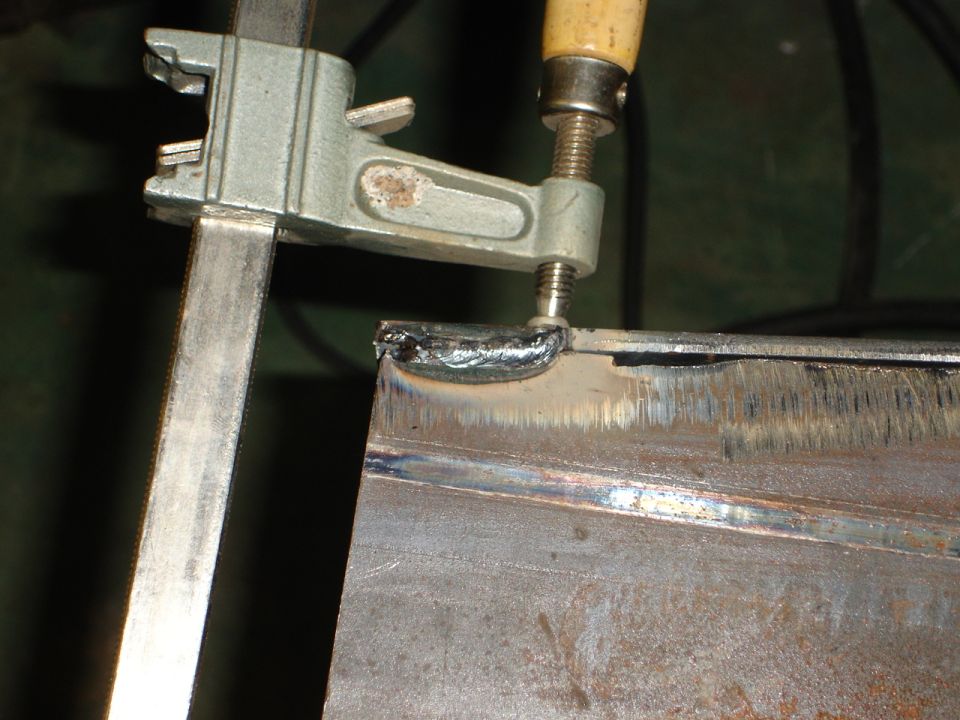 Clamp holding metal for welding, SuperMotors logo visible