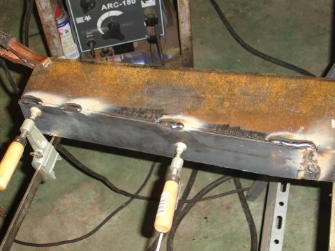 1989 Ford Bronco - Metal beam undergoing welding repairs, with clamps and a welding machine visible.