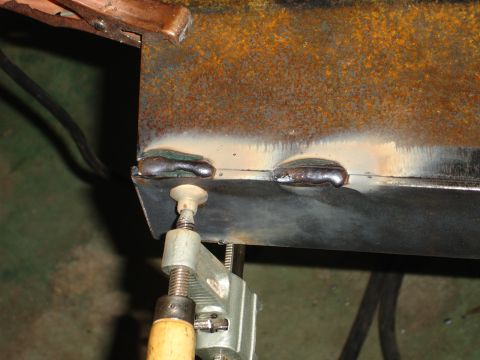 1989 Ford Bronco - Close-up of welding on a rusty metal part, secured with a clamp.