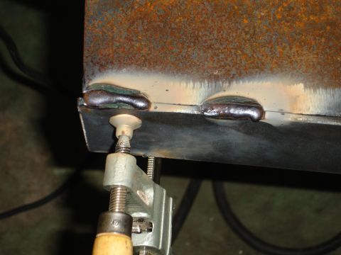 1989 Ford Bronco - Metal parts being welded together, secured by a clamp.