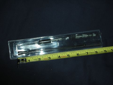 1998 Ford Crown Victoria - A slim chrome antenna mast in a clear plastic blister package laid on dark fabric, with a threaded base and a stepped tapered tip. A yellow…