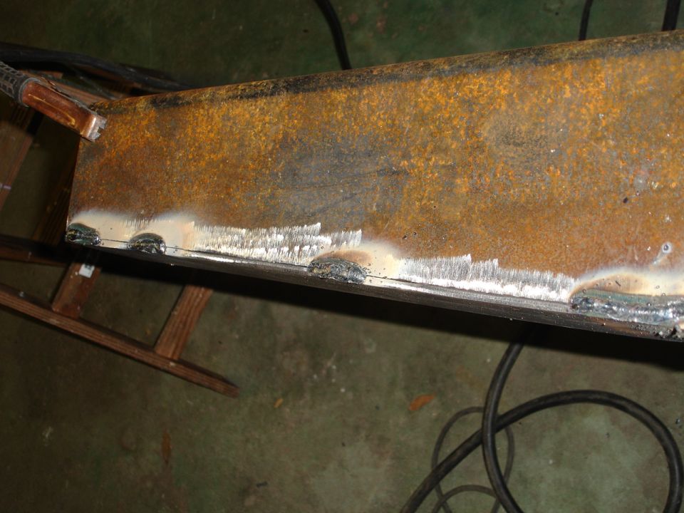 Welding on rusty metal beam with Supermotors logo visible