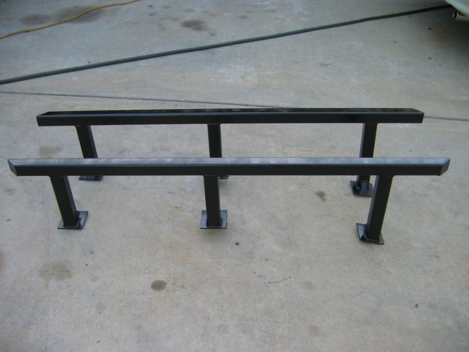 Pair of black metal running boards with square tube construction and mounting brackets