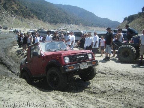 1987 Suzuki Samurai - Red 1987 Suzuki Samurai navigating a sandy off-road course with spectators.