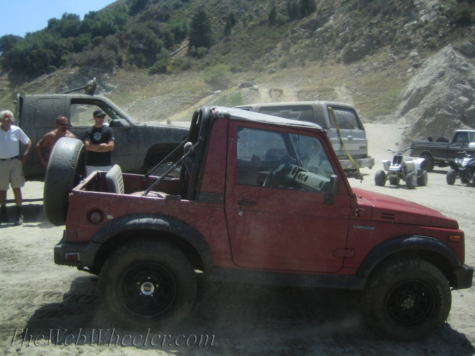 Red 1987 Suzuki Samurai with spare tire on back, off-roading