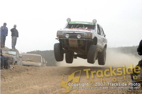 1992 Ford Explorer - This modified 1992 Ford Explorer takes flight during an off-road race, with other vehicles and spectators visible in the background.