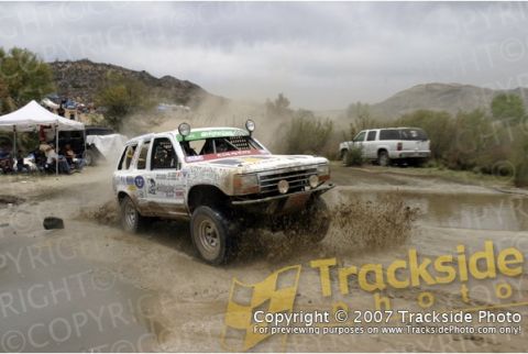 1992 Ford Explorer - A modified SUV races through a muddy terrain, kicking up water and dirt.