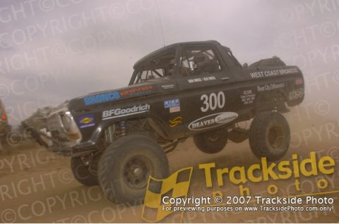 1992 Ford Explorer - A modified black off-road race truck, number 300, competes in a dusty event.