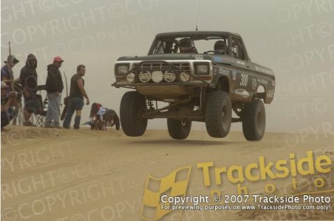 1992 Ford Explorer - This modified truck is airborne during a desert race, with spectators gathered on the side.