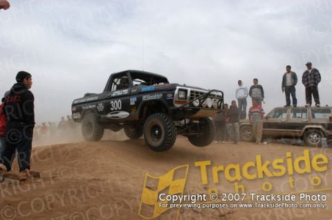 1992 Ford Explorer - A modified truck competes in an off-road race, kicking up dust as it jumps.