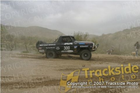 1992 Ford Explorer - A black off-road racing truck, number 300, kicks up dust on a dirt track.