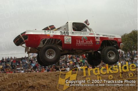 1992 Ford Explorer - A modified pickup truck soars through the air during a race event with spectators watching.