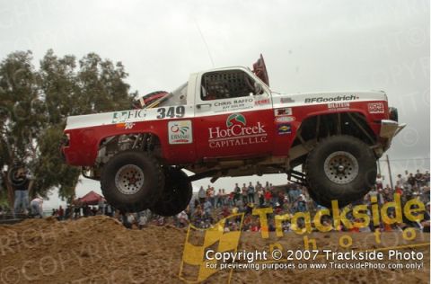 1992 Ford Explorer - A modified off-road truck jumps over a dirt obstacle during a race event.