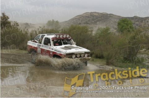 1992 Ford Explorer - Off-road truck navigates a muddy terrain, kicking up water as it drives through a shallow pool.