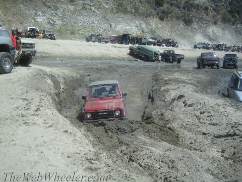 1987 Suzuki Samurai - Red 1987 Suzuki Samurai tackles a challenging mud pit at an off-road event.