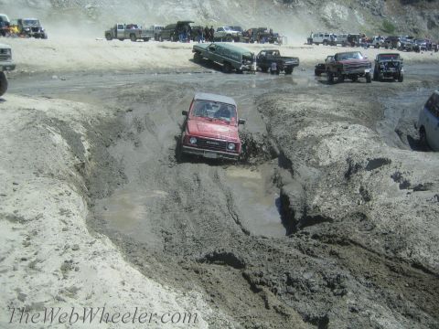 1987 Suzuki Samurai - Off-road event with multiple vehicles tackling a challenging muddy terrain.
