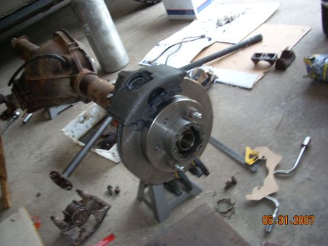 2000 Chevrolet Tahoe - A vehicle's rear axle and brake components are disassembled and laid out on the floor.