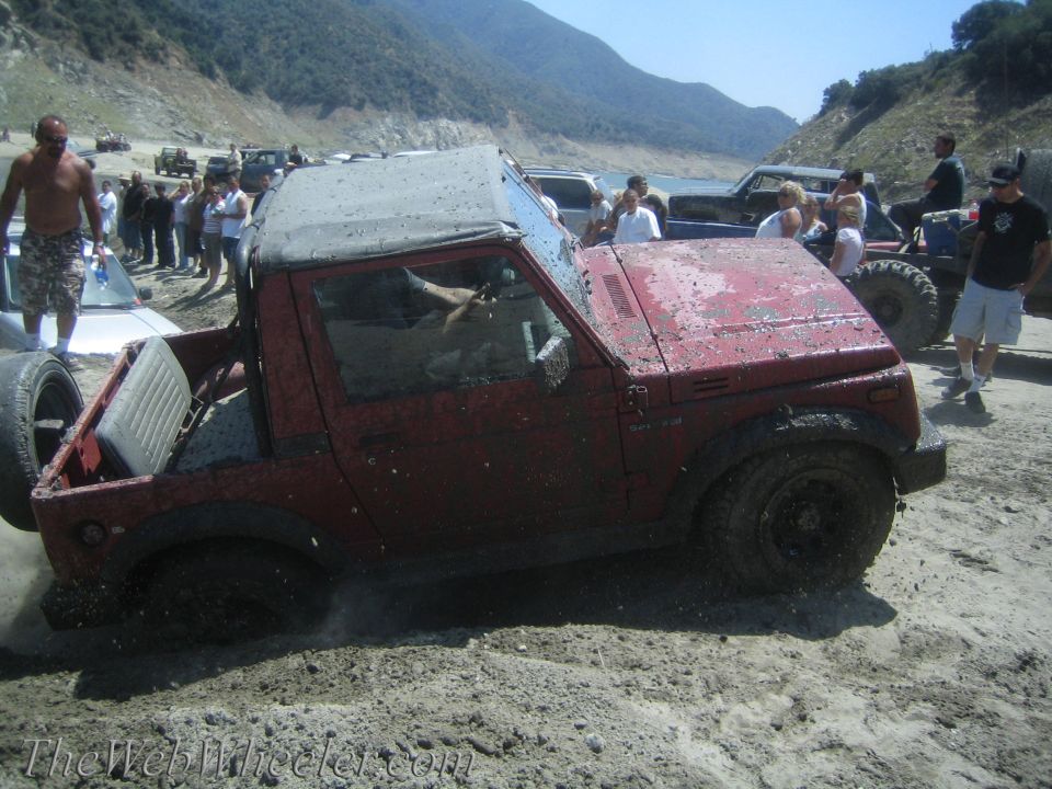 1987 Suzuki Samurai stuck in mud, with people watching and other vehicles nearby
