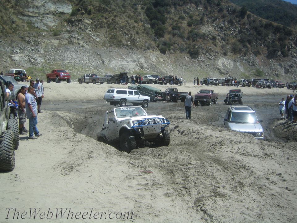 White 1987 Suzuki Samurai stuck in mud with blue bumper guard