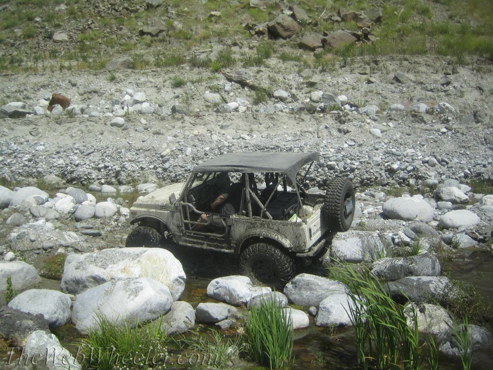 1987 Suzuki Samurai driving through a rocky stream